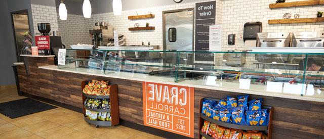 A modern and clean fast-food restaurant interior with an empty counter, menu boards on the wall, and a display rack with snacks.